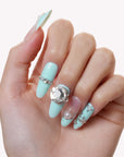 Hand model wearing Aqua Bijou press-on nails with mint blue and ivory tones, pearl accents, and a large crystal embellishment