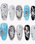 Flat lay of Artisian Orbit press-on nails with white, black, and blue accents, pearl details, and gem embellishments