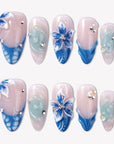 Azure Bloom press-on nails with pink bases, blue floral art, sculpted petals, pale aqua swirls, and silver rhinestones