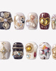 Baroque Treasures press-on nails with black, burgundy, and ivory designs, gold floral charms, pearls, rhinestones, and gemstone accents
