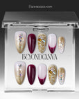 Berry Firelight press-on nails displayed in a clear BeyondCanva case with burgundy, blush pink, gold glitter, and gemstone accents