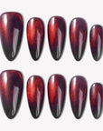 Bloody Tears press-on nails with glossy black bases, deep red cat eye shimmer, smoky blood-red gradient, and almond shapes