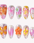 Bloom Pop pink press-on nails with raised orange butterflies, pastel flowers, pearls and a glossy ombre finish