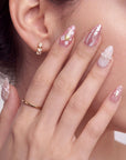 Model close-up wearing blush pink press-on nails with pearl accents and soft floral details.
