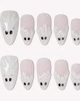 Boo Cuties press-on nails with soft white and pale pink bases, raised ghost shapes, black eyes, and tiny pink cheeks