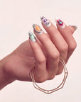 Hand model wearing Candy Chrome press-on nails with silver chrome outlines, pastel candy colors, star charm, glossy accents, and rhinestone details