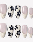 Chalk Floral press-on nails with nude pink bases, textured white French tips, and raised black flower designs