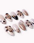 Angled flat lay of Chestnut Bloom press-on nails with nude pink bases, brown floral petals, black French accents, and rhinestone details