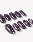 Angled flat lay of Cocoa Dots press-on nails with glossy dark brown bases and raised white polka dot designs