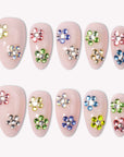 Crystal Dew handmade press on nails arranged in a white flat lay with colorful rhinestone flower accents