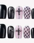 Dark Masquerade press-on nails with glossy black tips, pink nude bases, black rhinestone cross accents, and raised fishnet designs