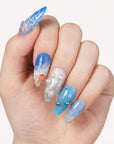 Hand model wearing Deep Sea Serenade handmade press-on nails with ocean blue waves, pearls, and starfish details.