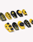 Dot Obsession press-on nails in black and yellow with bold polka dots arranged in a flat lay on a white background