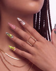 Close-up of a hand wearing multicolor floral press-on nails with pink, yellow, and green accents.