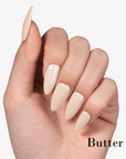 Hand model wearing Fall Essence Butter press-on nails in a creamy pale yellow shade with glossy almond-shaped tips