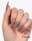 Hand model wearing Fall Essence Cocoa press-on nails in a taupe brown shade with glossy almond-shaped tips