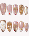 Flat lay of blush pink, white, and gold press-on nails with jeweled crosses, stars, and metallic swirl accents.