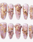 Gilded Petal Waltz press-on nails in soft lavender and gold with floral accents, pearls, and rhinestones arranged in a flat lay