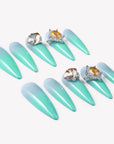 Flat lay of Glacier Jewel press-on nails arranged in two rows with icy blue ombré and yellow crystal embellishments