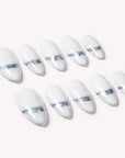 Diagonal flat lay of white press-on nails with iridescent chrome shimmer accents on a pale background.