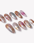 Flat lay of iridescent pearl press-on nail swatches in silver, blush pink, and gold foil