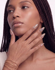Portrait of a hand model wearing gold floral stained-glass press-on nails with a white background.