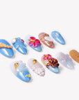 Angled flat lay of Island Echo blue and coral tropical press-on nails with flower, shell, turtle and sea details