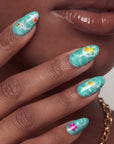 Close-up of a hand model wearing turquoise almond press-on nails with yellow and pink floral accents