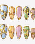 Jewel Mosaic press-on nails with pastel stained-glass panels, raised gold outlines, pearls, and colorful rhinestones
