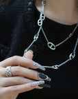 Lifestyle close-up of Lace & Pearls press-on nails with black matte tips, pearl trim, and white lace accents beside silver chain jewelry