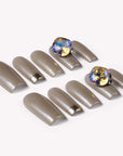 Flat lay of champagne metallic press-on nails with two iridescent gemstone accents