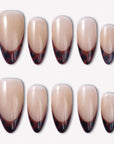 Leopard French press-on nails with glossy nude bases and deep brown black animal print French tips arranged in a full set