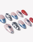 Angled flat lay of Liquid Mercury press-on nails with silver chrome swirls, blue gray French tips, nude pink bases, and red textured accents