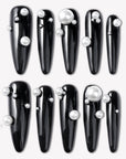Flat lay of Louboutin Pearl Noir press-on nails with glossy black finish and pearl embellishments
