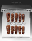 Packaging display of Luxurious Treasure brown square press-on nails in a clear BeyondCanva case with gold, amber, and clear rhinestone gems