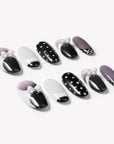 Flat lay of black and white press-on nails with polka dots and white bow accents arranged on a white background