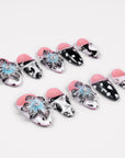 Angled flat lay of Midnight Bloom pink, navy and white press-on nails with blue flowers, polka dots and rhinestones