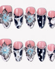 Midnight Bloom pink and navy press-on nails with blue floral charms, white dots and rhinestone accents in a flat lay
