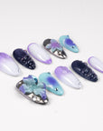 Angled flat lay of Moon Orchid purple, aqua, white and black press-on nails with raised orchids, blue gems and shimmer