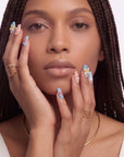 A front-facing hand model wearing blue floral press-on nails with pearl and star accents