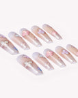 Opal Whisper press-on nails in pale pink and clear shimmer with white flower accents arranged on a white background