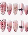 Parisian Charm press-on nails with pink bows, black polka dots, lace, floral art, stripes, and glossy pink tips