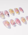 Angled flat lay of Pastel Bloom pink iridescent press-on nails with raised flowers, pearls and silver beads