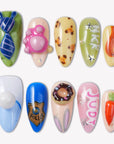 Flat lay of cartoon-themed press-on nail swatches with blue, pink, green, and orange character-inspired accents