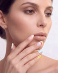 Face close-up of a hand model wearing handmade press-on nails with blue stripes and fruit accents.