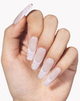 Hand model wearing Pink Confetti press-on nails with sheer nude pink square bases and sparkling pink silver glitter French tips