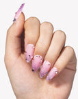 Hand model wearing Pink Fairy Dust press-on nails with pink shimmer gradients, cat-eye sparkle, and rhinestone accents