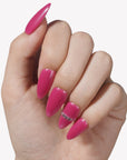 Close-up of a hand wearing glossy hot pink press-on nails with a crystal accent.