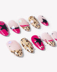 Flat lay of Pop Punk press-on nails with hot pink tips, leopard print accents, black star designs, and small rhinestones