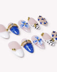 Flat lay of Porcelain Azure handmade press-on nails with cobalt blue, white, nude, floral, and gold bead accents.